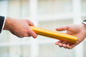 Two hands exchanging a yellow document tube related to VA disability compensation.