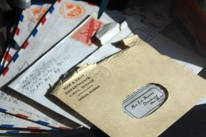 Vintage envelopes and letters with postage stamps and postmarks, some marked "Veterans Affairs official business," on a desk.